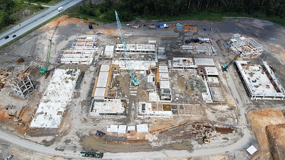 Aerial view of a large greenfield site with foundations and a crawler crane